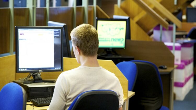Image of male student sat in front of a computer workstation.