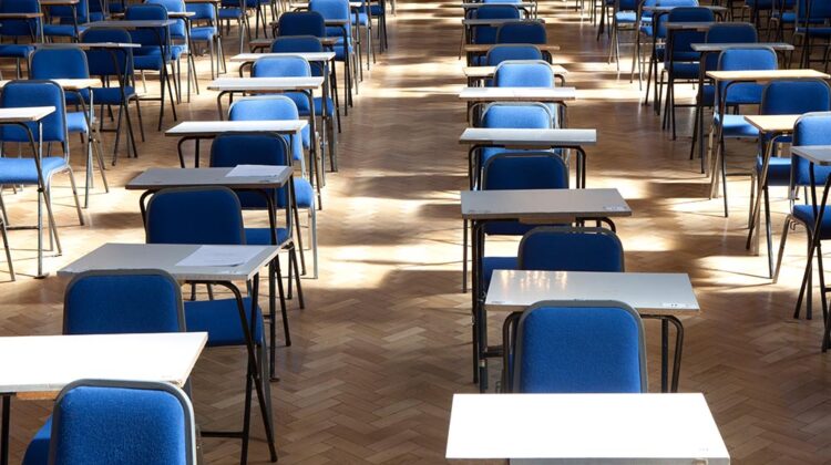 Image of empty exam desks and chairs in a large exam room