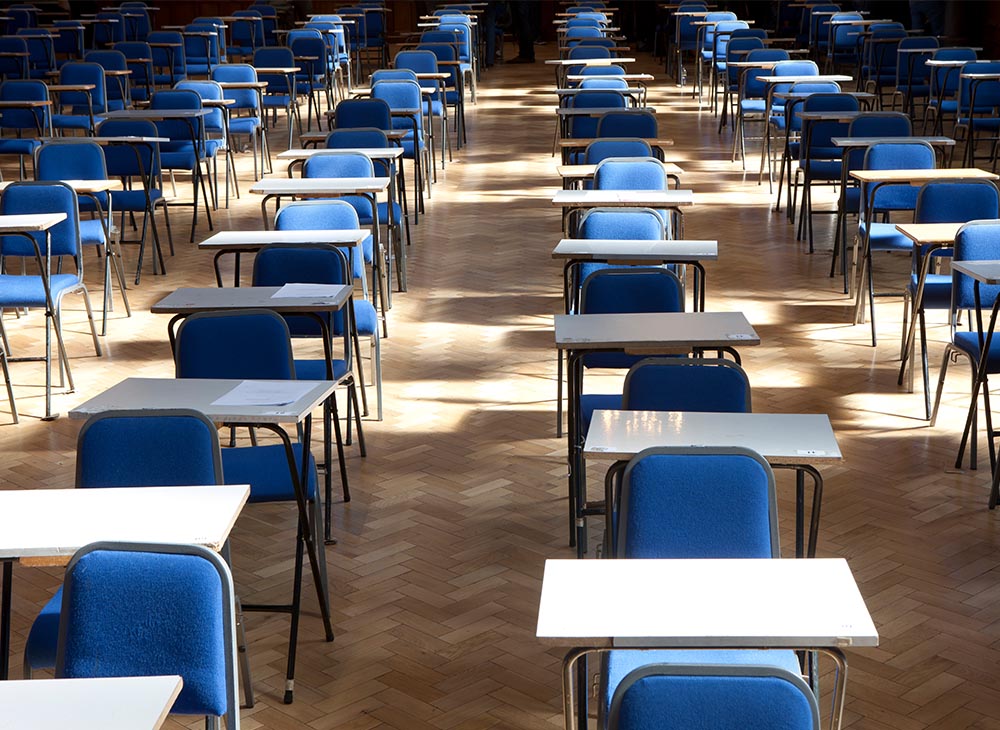 Image of empty exam desks and chairs in a large exam room