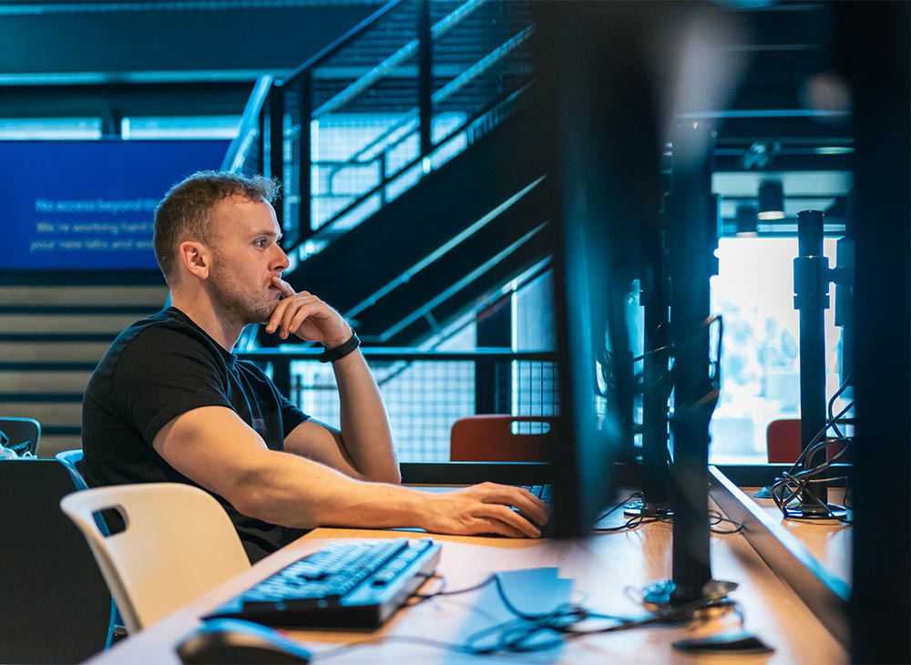 A person sat at a computer cluster computer, they are looking at the screen