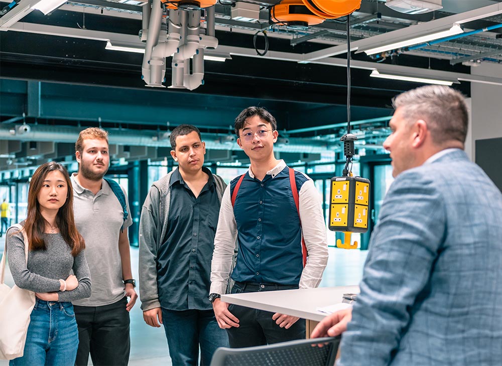 A member of staff speaking to four students while stood in one of the MECD practical teaching spaces