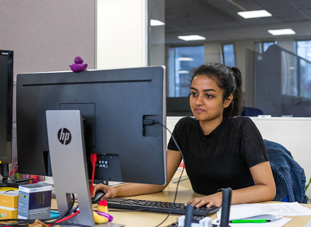 Student looking at computer with one hand on the mouse, the other on the keyboard