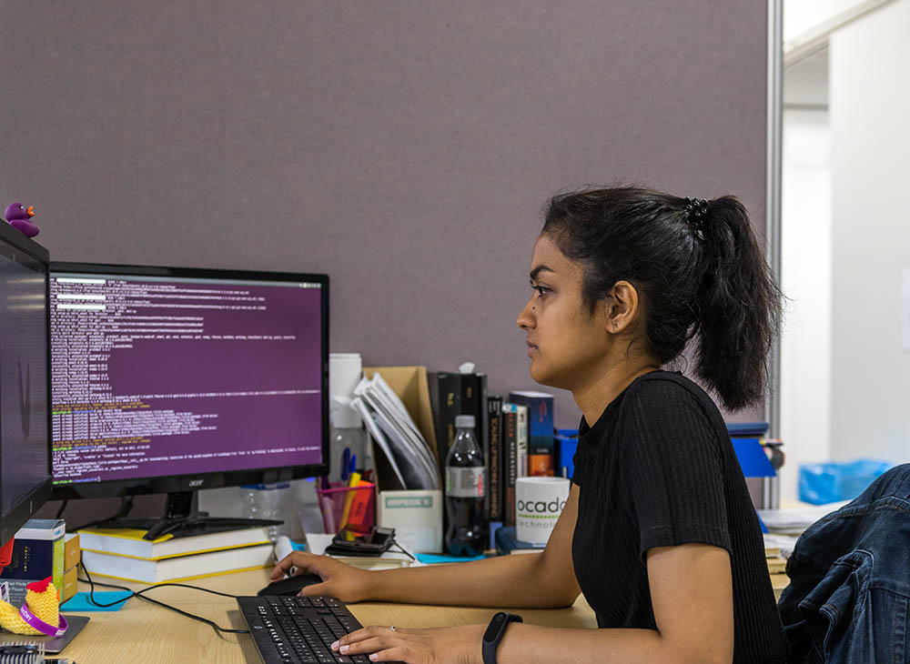 Student looking at a computer with one hand on mouse and other hand on keyboard